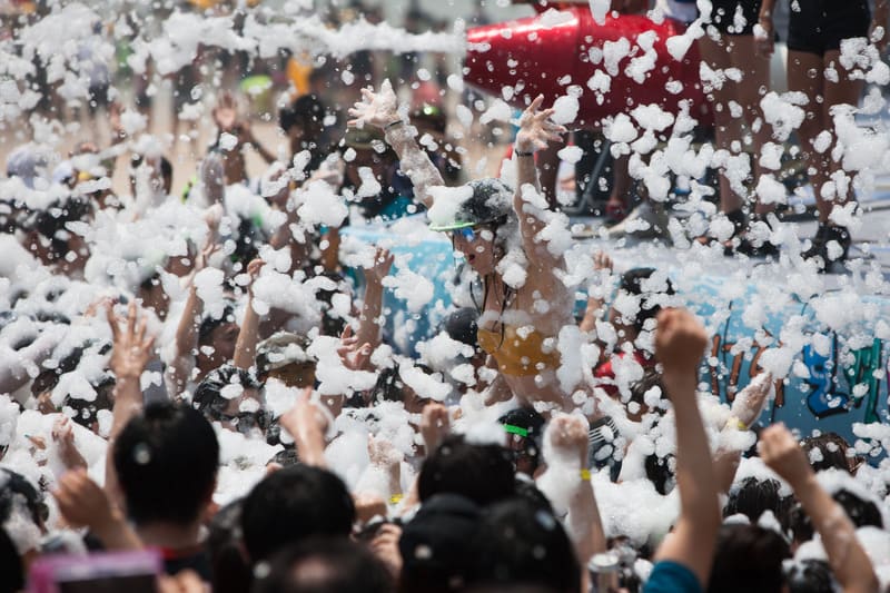 Festival-goers dancing in a shower of foam at the Boryeong Mud Festival