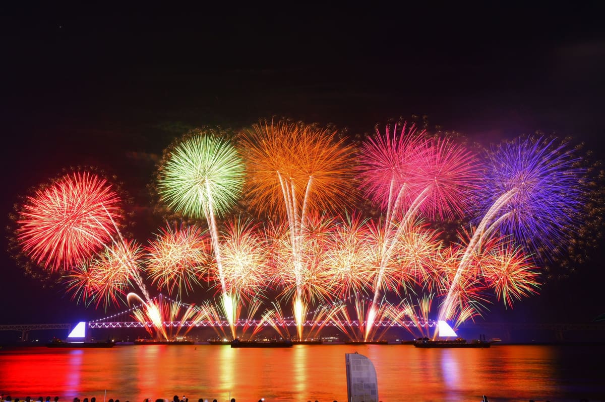 Multicoloured shells bursting above Gwangan Bridge, seen across the water from Gwangalli, November 2023