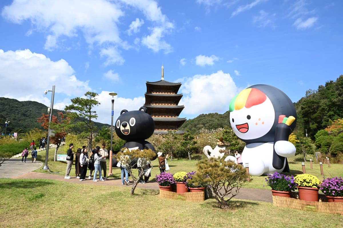Giant inflatable characters on the lawn beside the wooden pagoda in the festival park, 2025