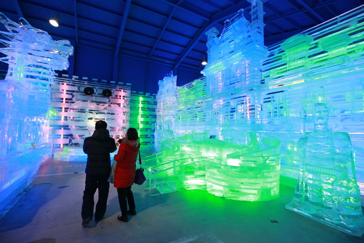 Visitors among illuminated ice sculptures in the festival's indoor ice plaza