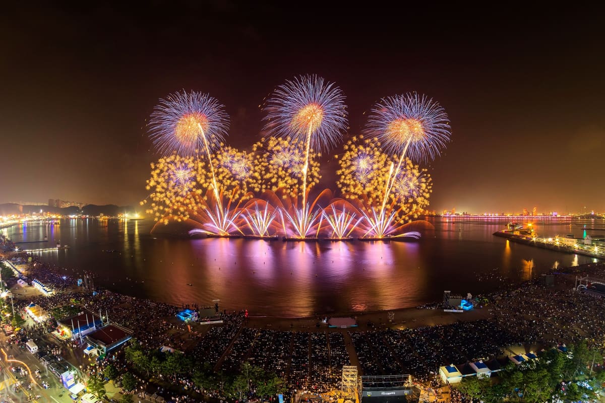Crowds packing Yeongildae Beach as fireworks burst over the bay, seen from above, 2017