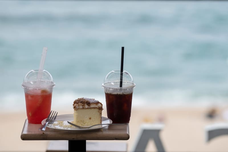 Iced drinks and cake on a café table overlooking Anmok Beach on Gangneung's coffee street