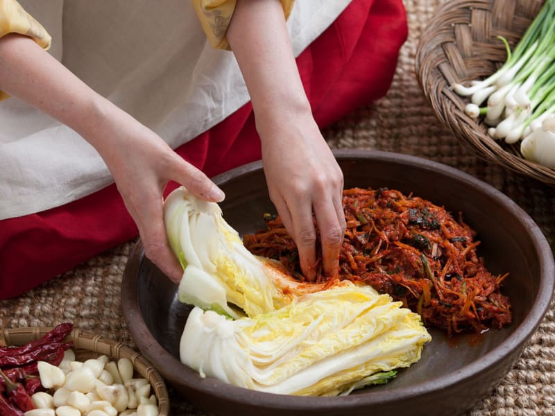 Hands rubbing red pepper seasoning into salted cabbage during kimjang, Korea's winter kimchi-making (photo taken in Seoul)