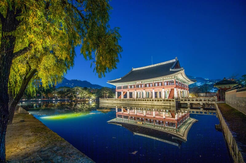 Gyeonghoeru Pavilion at Gyeongbokgung Palace lit up at night and reflected in its pond