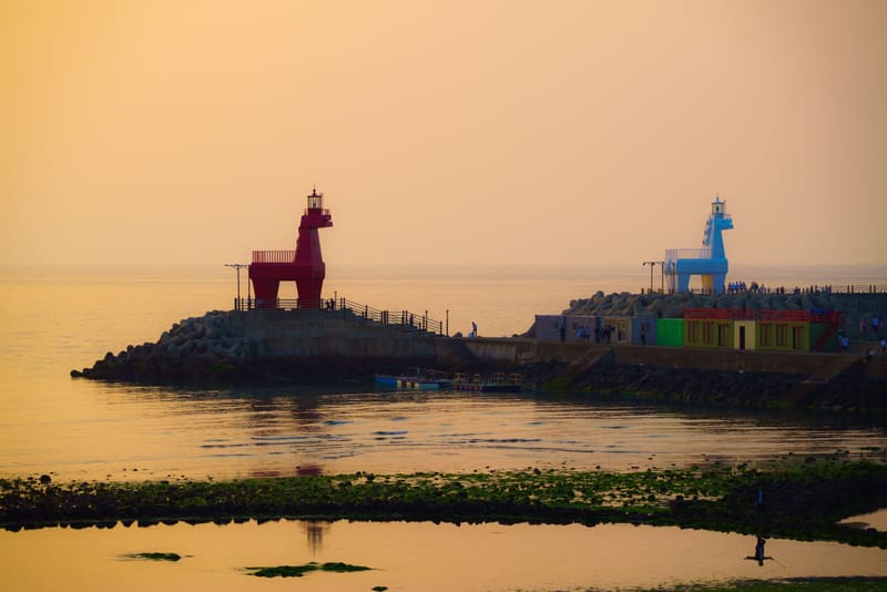 The red and white horse-shaped lighthouses of Iho Tewoo Beach at sunset
