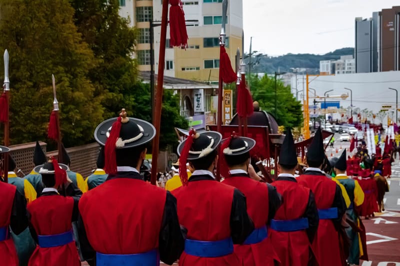 Soldiers in red uniforms marching in the King Jeongjo royal procession reenactment held with the 2023 Suwon Hwaseong Cultural Festival