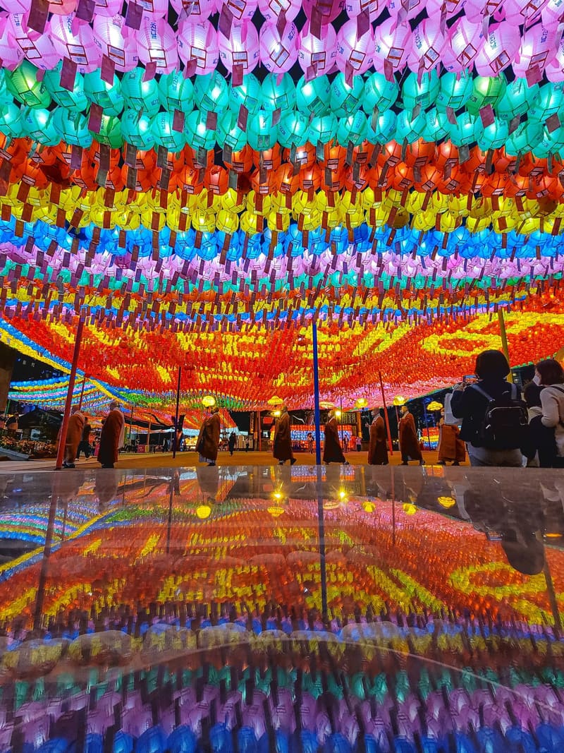 Rows of lotus lanterns over the courtyard of Jogyesa Temple in Seoul before Buddha's Birthday, with monks walking beneath